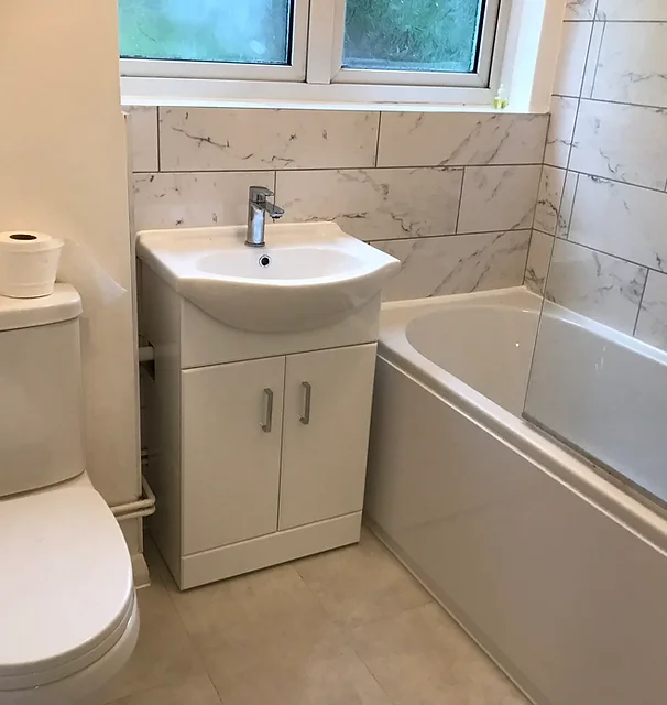 Small white bathroom with toilet and bath