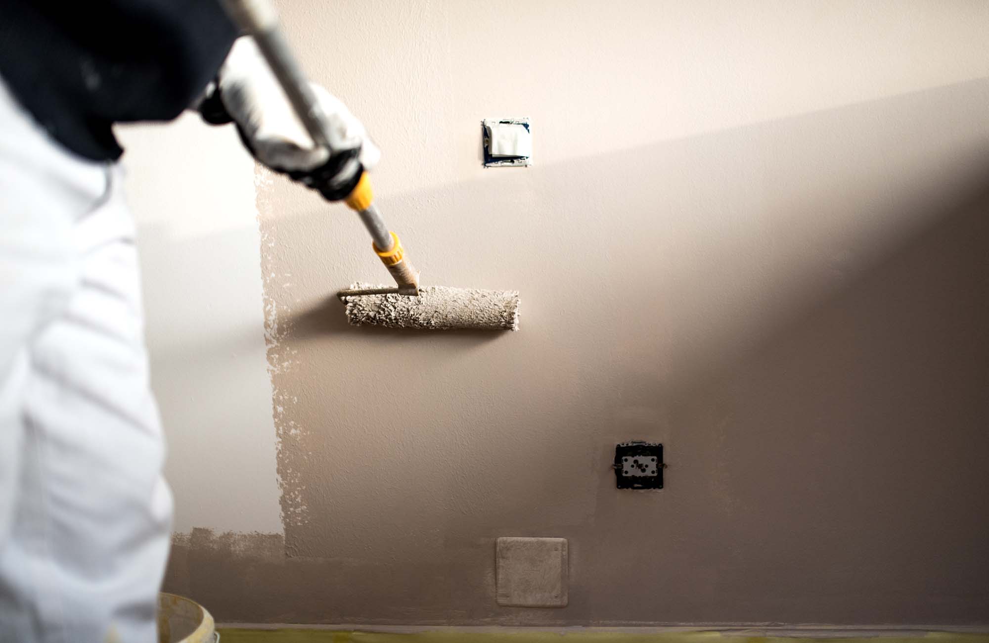 Handy man decorating walls with paint. Construction plaster worker painting and renovating with professional tools