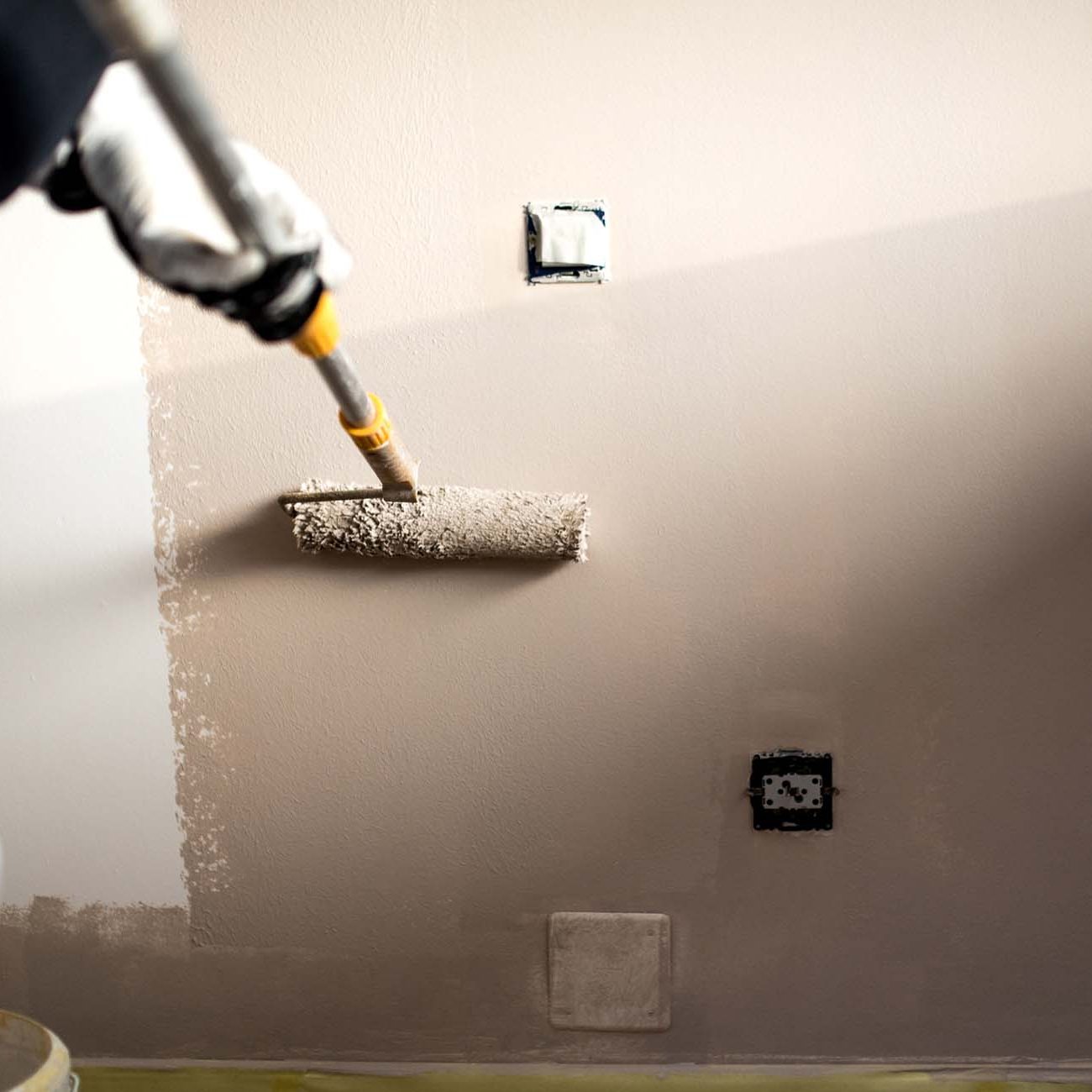 Handy man decorating walls with paint. Construction plaster worker painting and renovating with professional tools